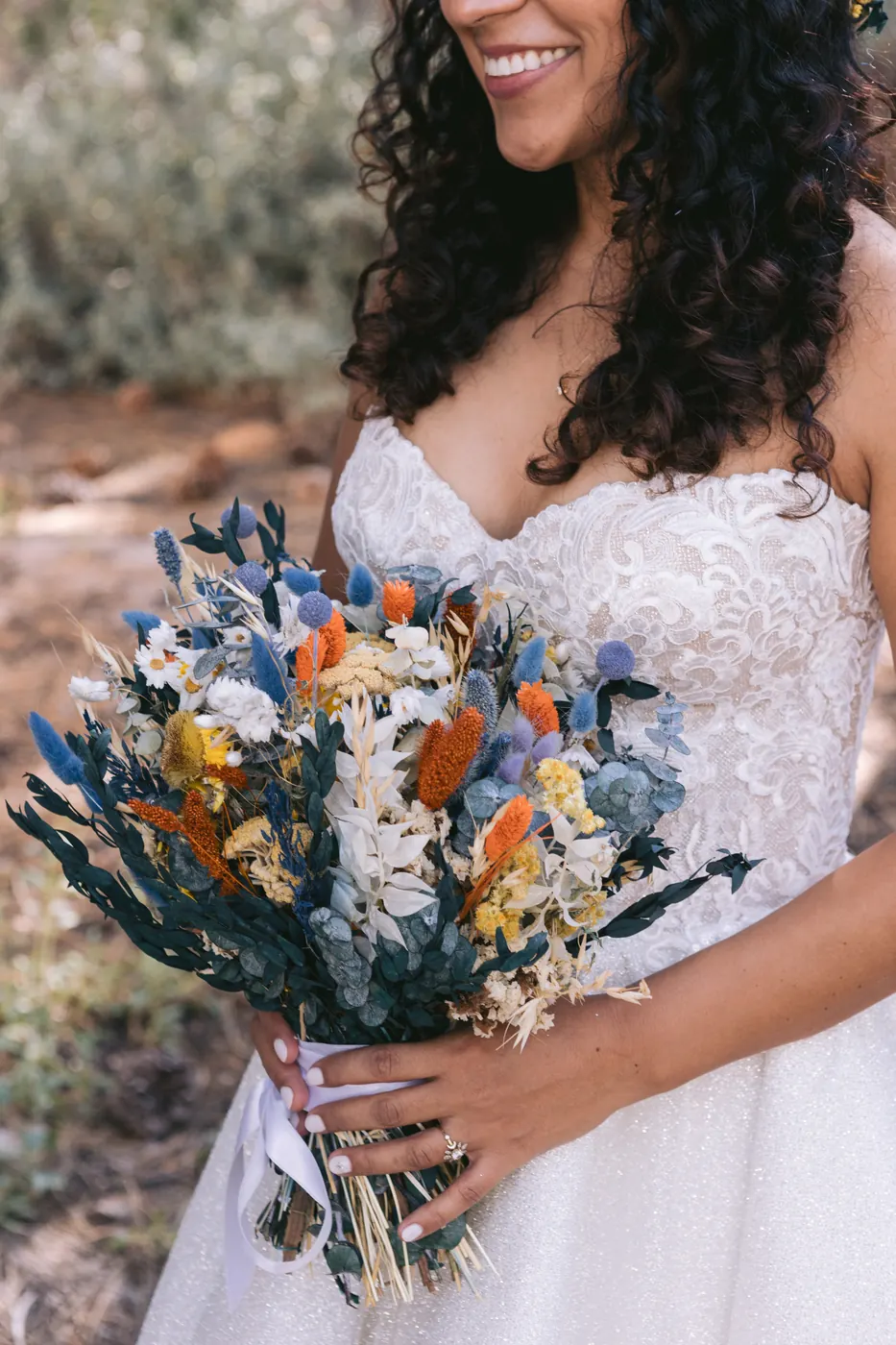 Bride holding a dried-flower bouquet in dusty blue, cream and orange