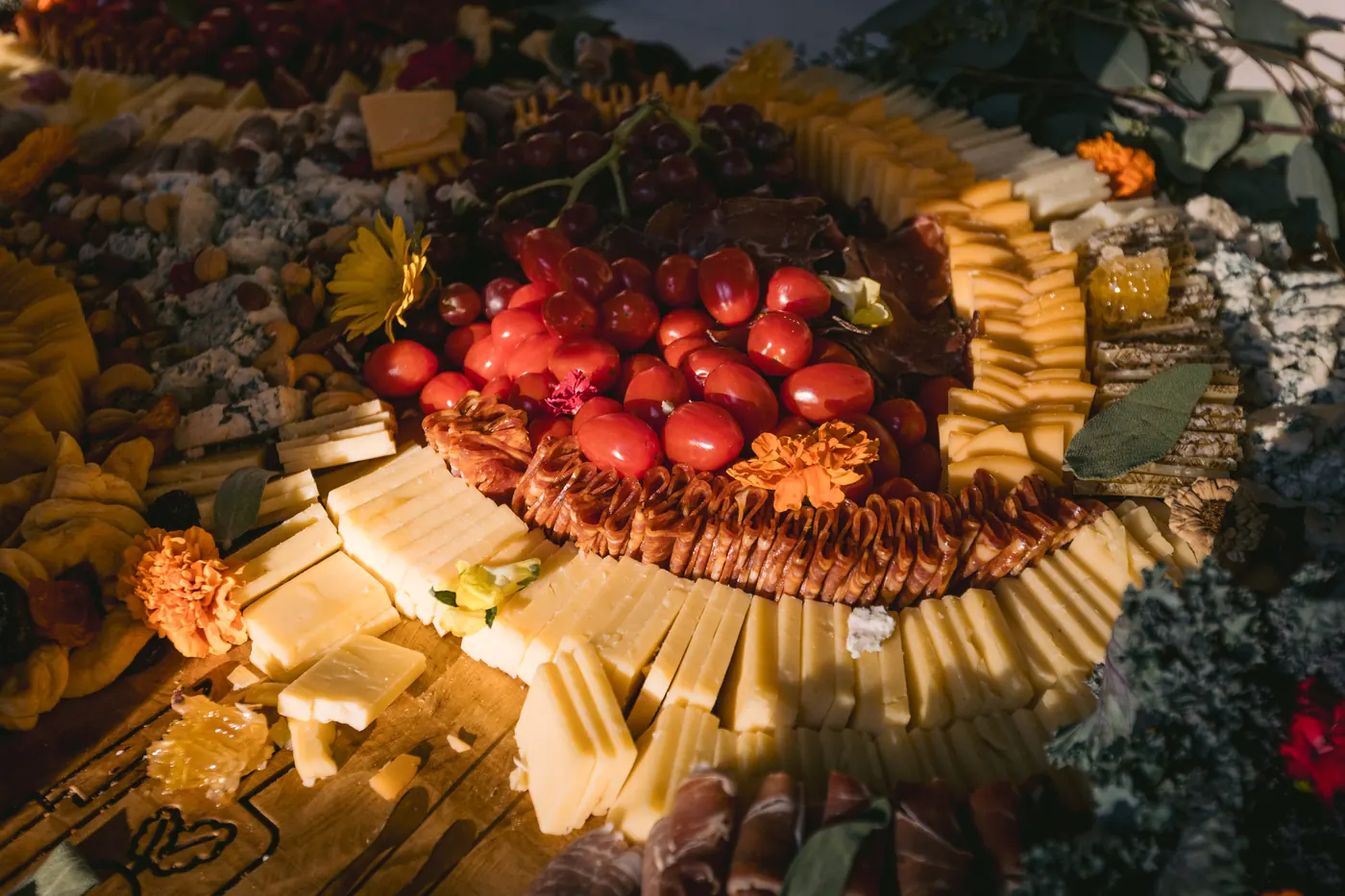 Overhead view of a grazing table with cheeses, cured meats, berries and marigolds