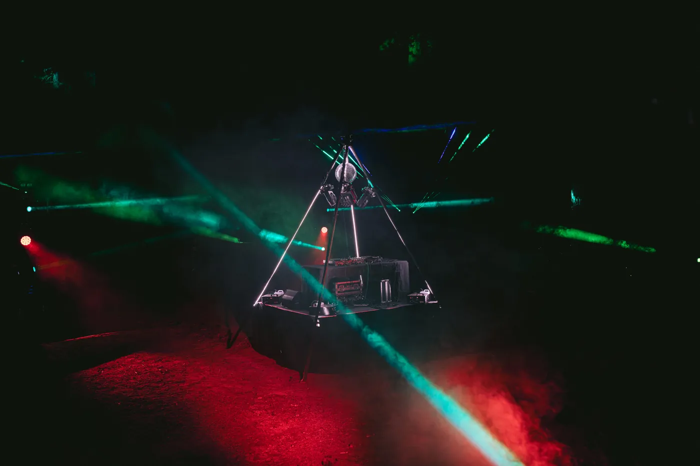 Green laser beams sweeping over a lit triangle DJ booth